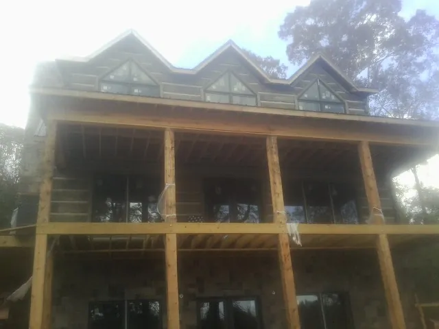 Dormers and porch framing on a large log home under construction — Roof Coating work by our crew in Primm Springs