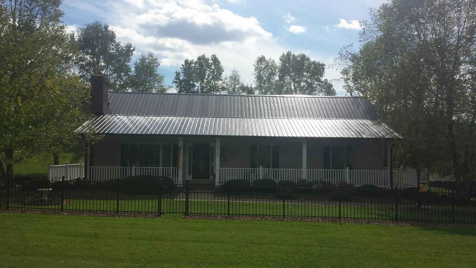 Gray metal roof on a brick ranch with a full width front porch — Gutter Guard Installation work by our crew in Primm Springs