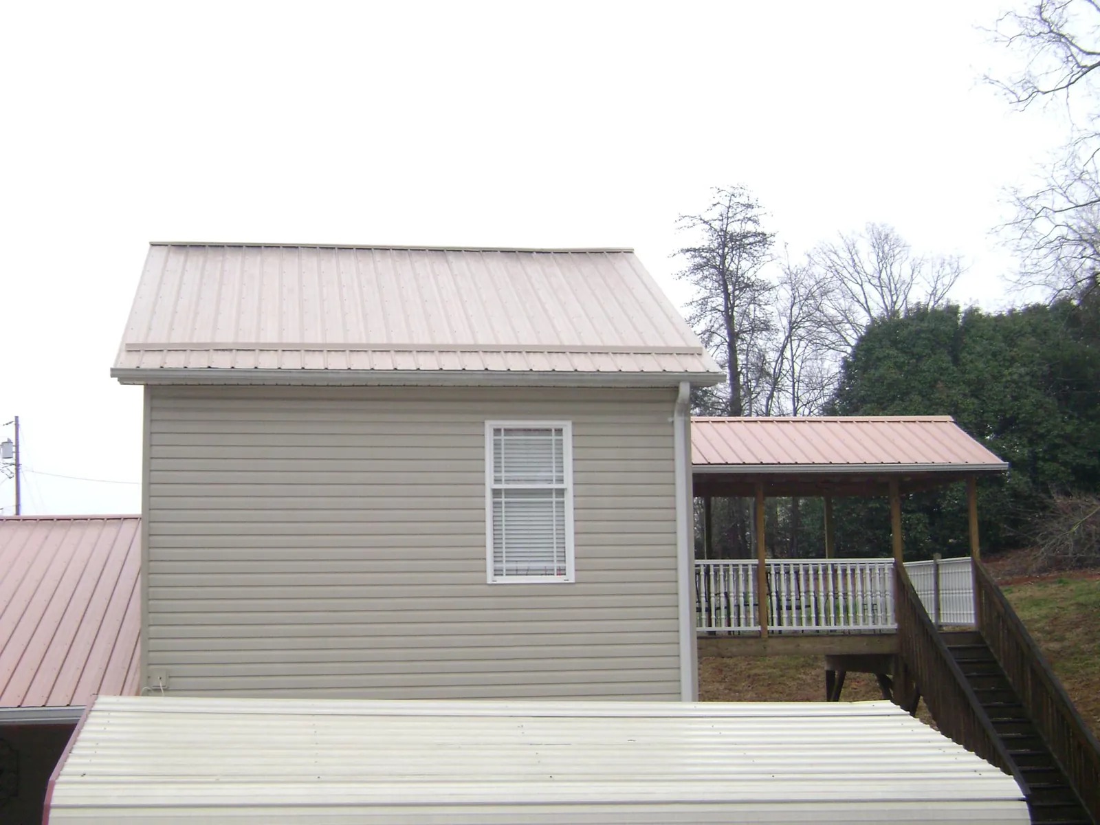 Tan metal roofs on a two story addition and attached porch, from a Roof Replacement job in Primm Springs