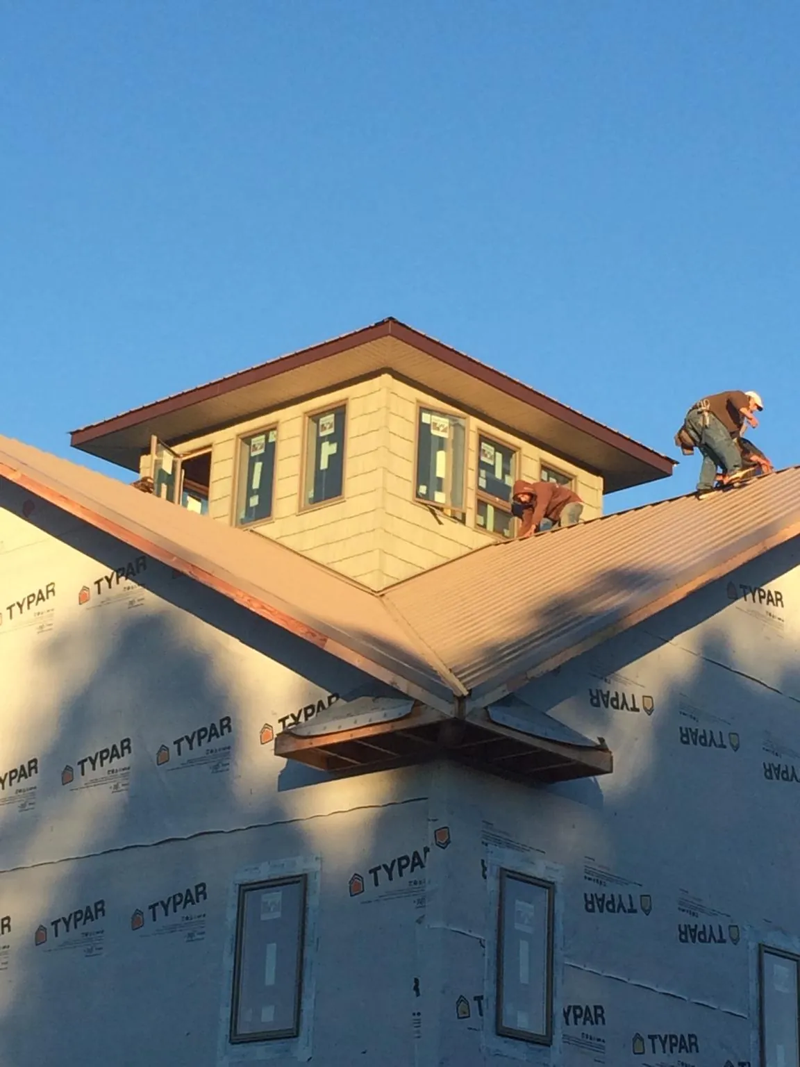 Roofers working around a rooftop cupola on a new metal roof at sunset — Roof Waterproofing in Primm Springs by Roofing Brothers